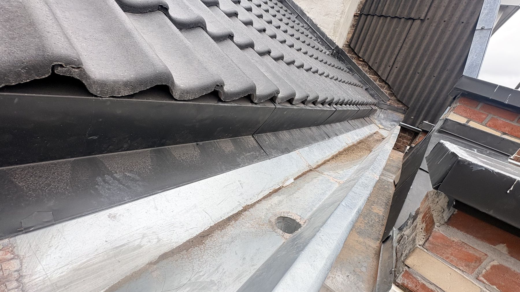 Bord de toiture en tuiles noires avec finition en zinc et chéneau